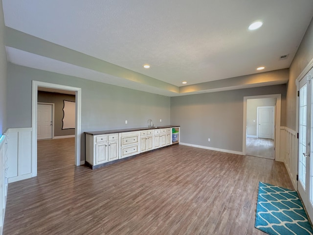 unfurnished room featuring recessed lighting, indoor wet bar, dark wood-style floors, and visible vents