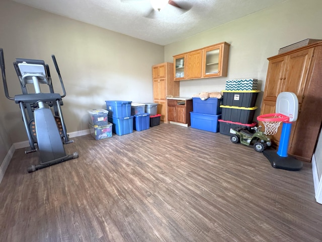 rec room featuring wood finished floors, a textured ceiling, baseboards, and ceiling fan