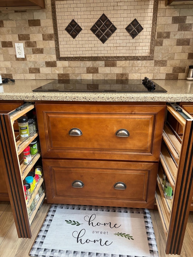 room details with black electric stovetop, brown cabinetry, and tasteful backsplash