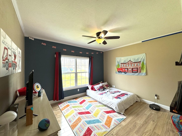 bedroom with a textured ceiling, baseboards, wood finished floors, ceiling fan, and crown molding