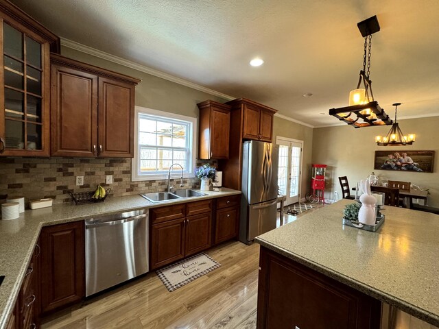 kitchen featuring crown molding, light wood-style floors, appliances with stainless steel finishes, a sink, and plenty of natural light