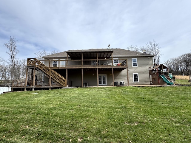 back of property featuring a lawn, a wooden deck, stairs, and a playground