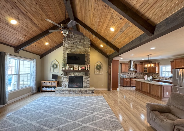living room with baseboards, vaulted ceiling with beams, wooden ceiling, and ceiling fan with notable chandelier