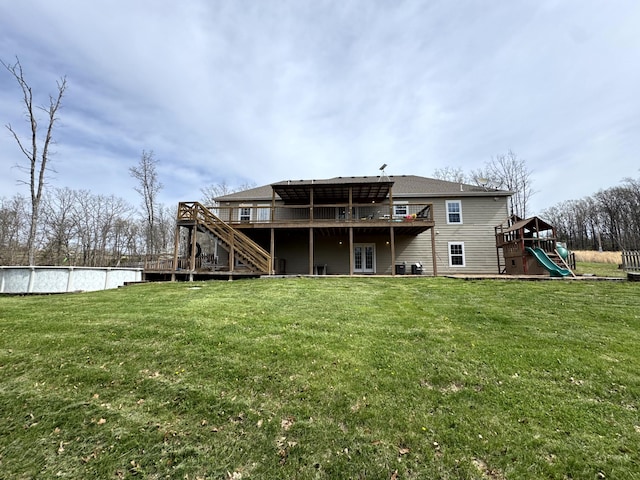 rear view of property with a lawn, a wooden deck, stairway, and an outdoor pool