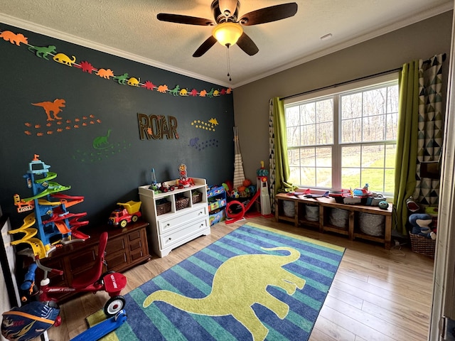 playroom with ornamental molding, ceiling fan, wood finished floors, and a textured ceiling