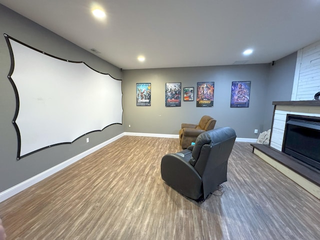 cinema with baseboards, a glass covered fireplace, wood finished floors, and recessed lighting