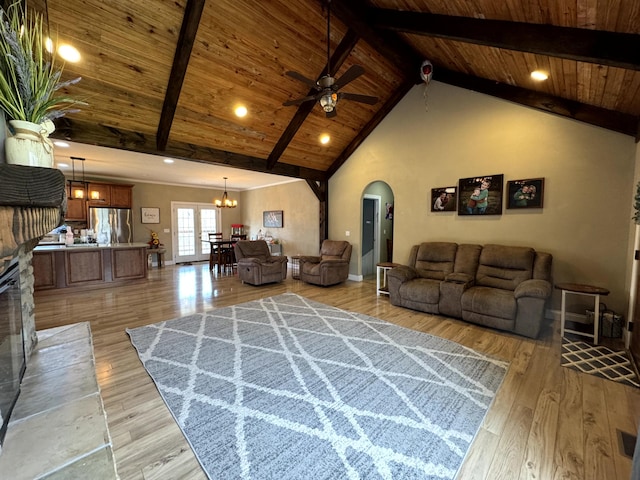 living room with beam ceiling, ceiling fan with notable chandelier, arched walkways, and wood ceiling