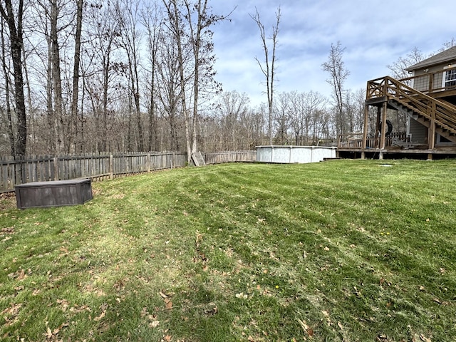 view of yard with a wooden deck, a fenced backyard, and stairs