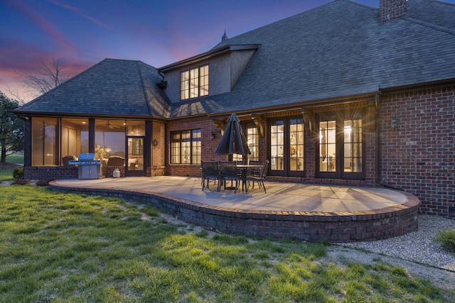 845 W Farm Road 96, Springfield, MO 65803 - back of house at dusk with a lawn, a shingled roof, brick siding, and a patio