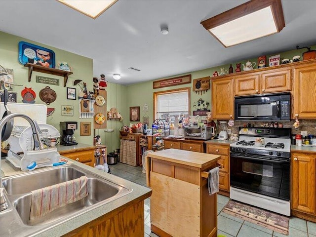 kitchen with a sink, tasteful backsplash, light tile patterned flooring, gas stove, and black microwave