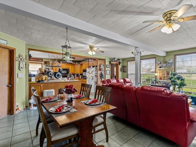 dining area with a ceiling fan, beam ceiling, and light tile patterned flooring