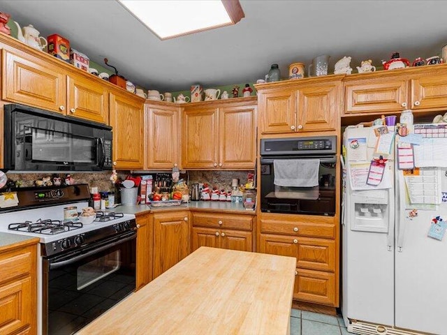 kitchen with black appliances, backsplash, brown cabinets, and light tile patterned floors