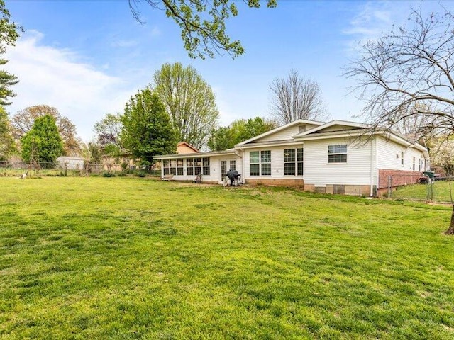 rear view of property featuring a lawn and fence