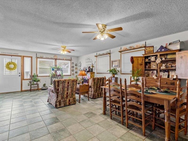 dining space with baseboards, a ceiling fan, and a textured ceiling