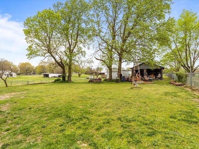 view of yard with fence, an outdoor structure, and an outbuilding