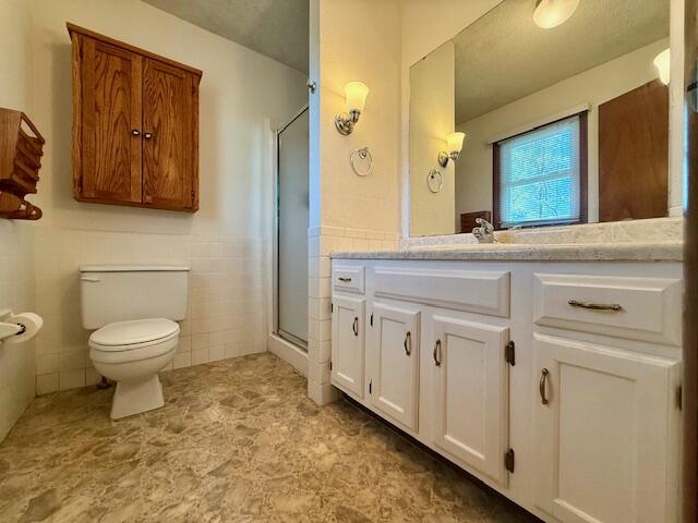 700 Ridgeway, Mountain View, MO 65548 - full bath featuring a wainscoted wall, toilet, vanity, tile walls, and a stall shower