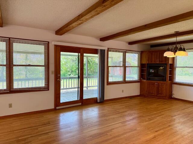 700 Ridgeway, Mountain View, MO 65548 - unfurnished living room with a chandelier, a textured ceiling, light wood finished floors, and baseboards