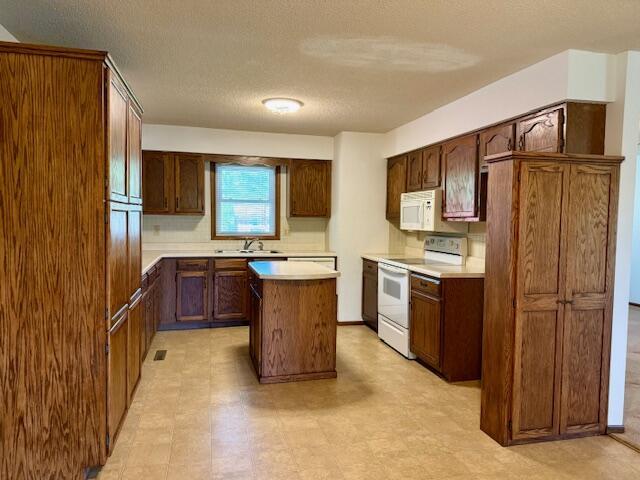 700 Ridgeway, Mountain View, MO 65548 - kitchen with a textured ceiling, a sink, white appliances, light countertops, and a kitchen island