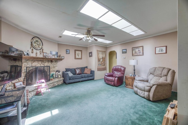 living room with arched walkways, carpet floors, a ceiling fan, crown molding, and a fireplace