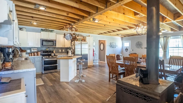 kitchen featuring a center island, wood finished floors, decorative backsplash, stainless steel appliances, and white cabinets