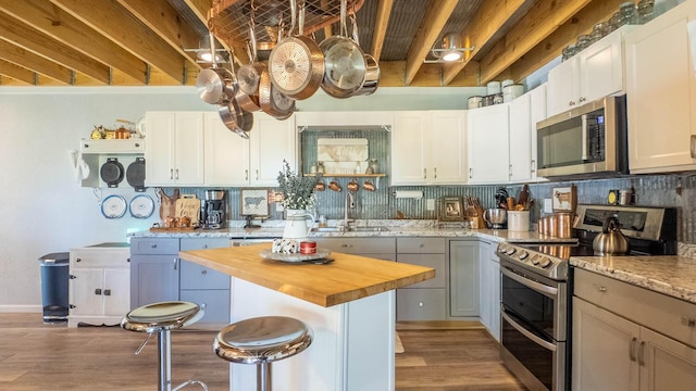 kitchen featuring stainless steel appliances, light wood-style floors, a sink, and wooden counters