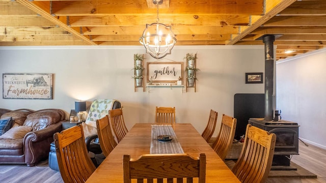 dining room with an inviting chandelier, a wood stove, and wood finished floors