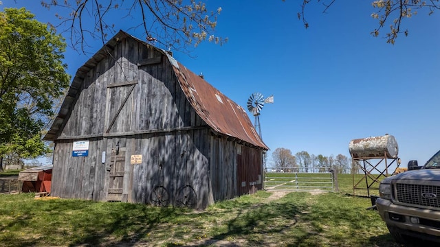 view of barn featuring fence and a lawn