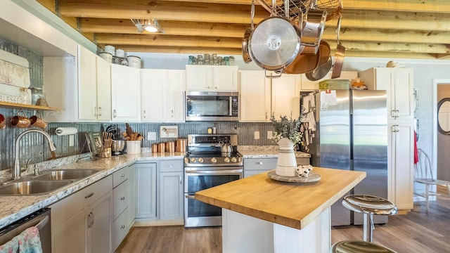 kitchen featuring stainless steel appliances, wood finished floors, a sink, and wooden counters
