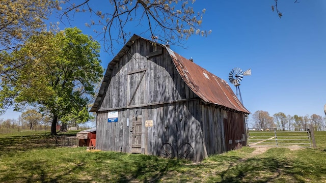 view of barn with fence and a yard