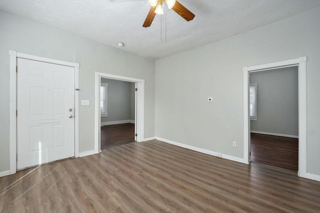 empty room featuring ceiling fan, baseboards, wood finished floors, and a textured ceiling