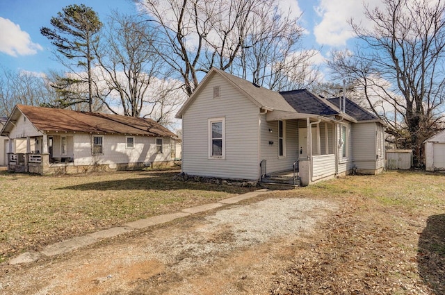 bungalow-style house with a front lawn, an outbuilding, and covered porch