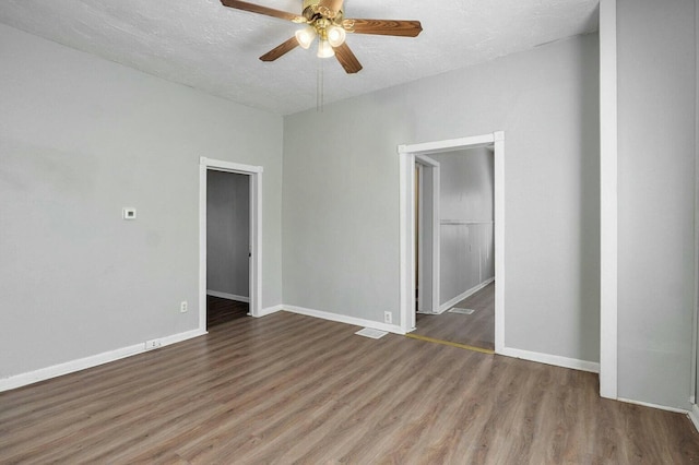 spare room featuring ceiling fan, baseboards, wood finished floors, and a textured ceiling