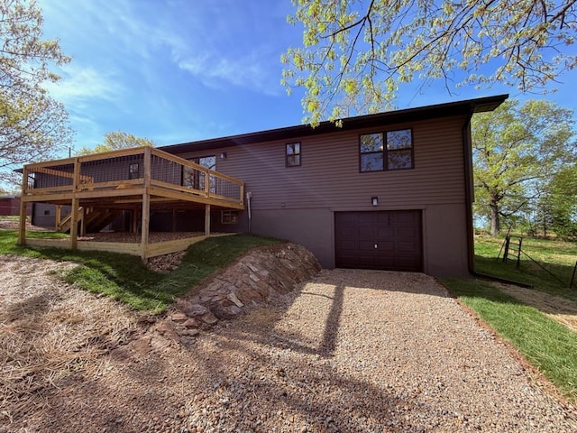 back of house with an attached garage, driveway, and a deck