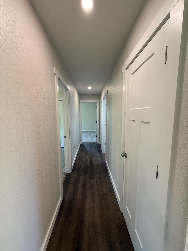 hall with dark wood finished floors, baseboards, and recessed lighting