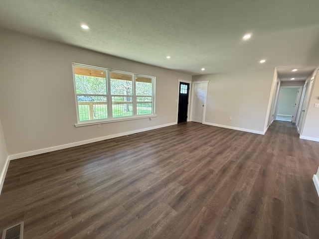 unfurnished living room with dark wood-type flooring, visible vents, baseboards, and recessed lighting