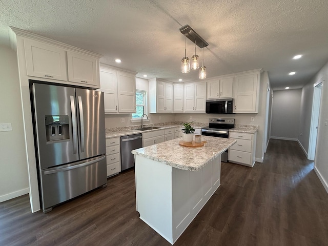 kitchen with a textured ceiling, a sink, stainless steel appliances, white cabinets, and baseboards