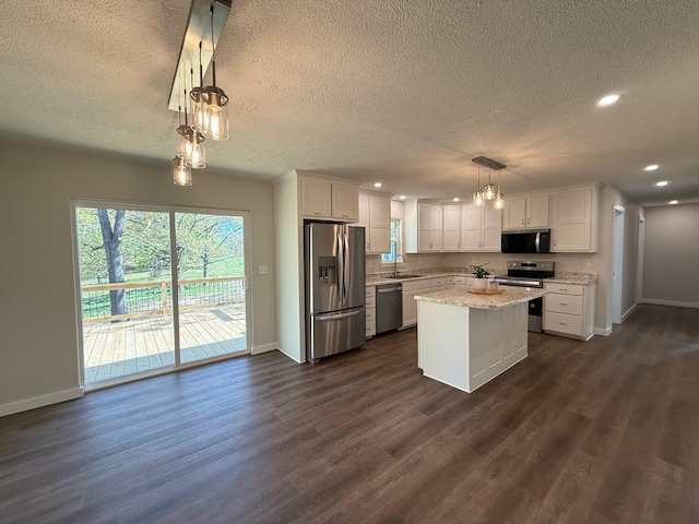 kitchen featuring a textured ceiling, appliances with stainless steel finishes, baseboards, and a sink