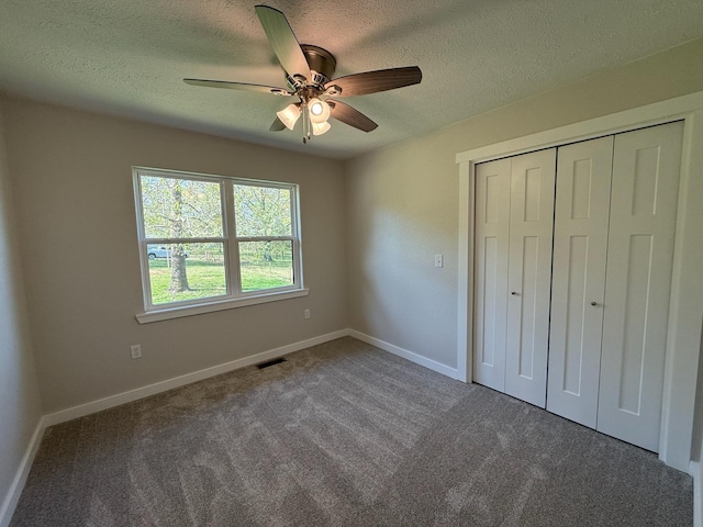 unfurnished bedroom featuring a closet, a textured ceiling, visible vents, and carpet