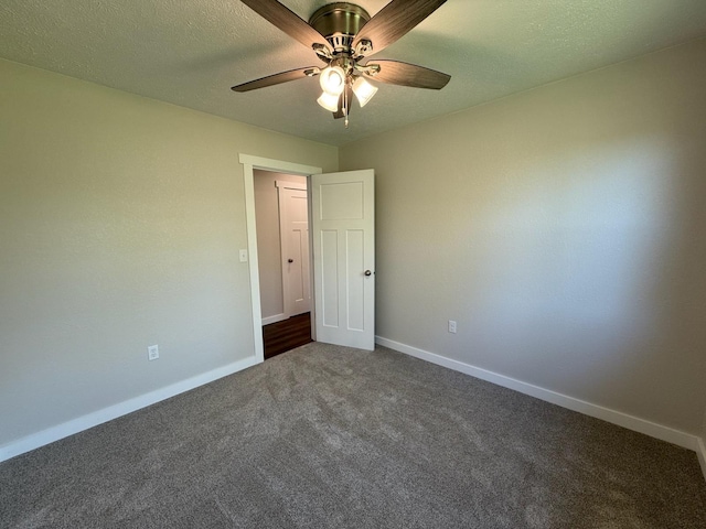 empty room featuring dark colored carpet, baseboards, and ceiling fan