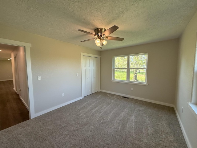 unfurnished bedroom featuring baseboards, carpet, a textured ceiling, and a closet