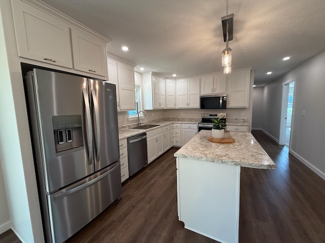 kitchen featuring a sink, dark wood-type flooring, a kitchen island, appliances with stainless steel finishes, and white cabinetry