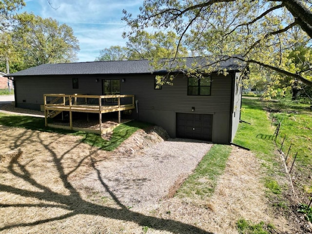 back of property with fence, a wooden deck, gravel driveway, and a garage