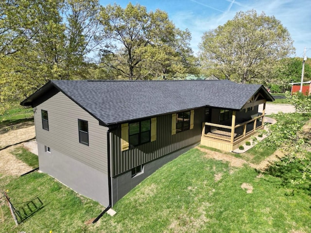 back of property featuring a lawn, roof with shingles, and a porch