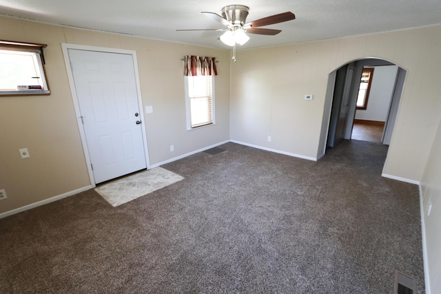 419 E Olive St, Bolivar, MO 65613 - interior space with dark colored carpet, arched walkways, baseboards, visible vents, and a ceiling fan