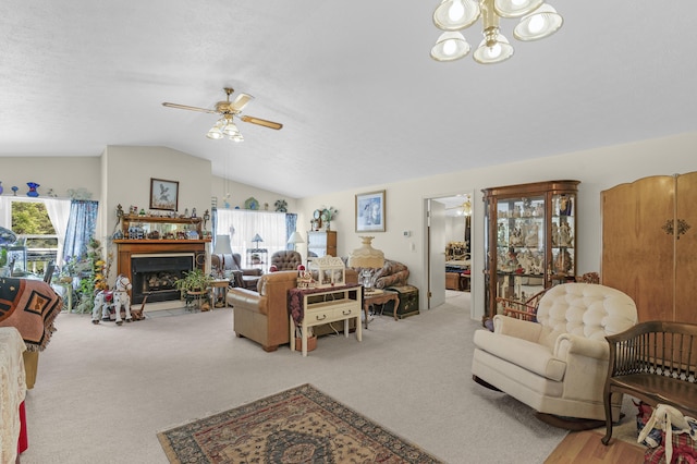 living area featuring a fireplace with flush hearth, carpet, ceiling fan with notable chandelier, and lofted ceiling
