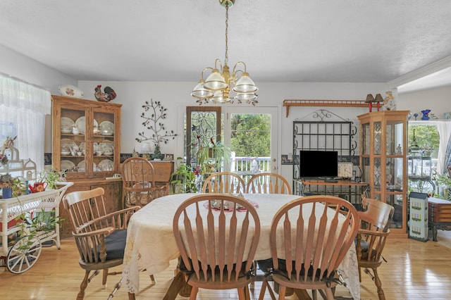 dining area featuring a textured ceiling, a chandelier, and light wood-style floors
