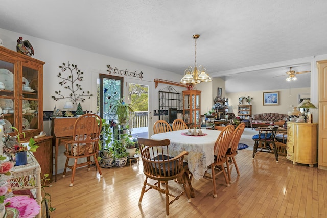dining space with a textured ceiling, light wood-style flooring, and a notable chandelier