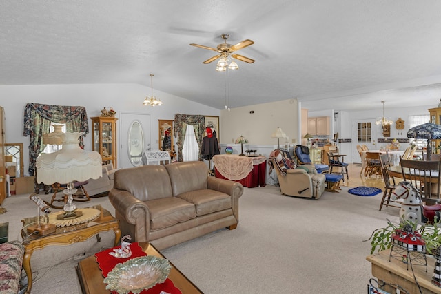 living area featuring ceiling fan with notable chandelier, light carpet, and vaulted ceiling