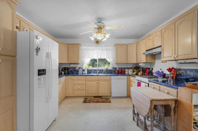 kitchen featuring dark countertops, under cabinet range hood, light brown cabinetry, and white appliances