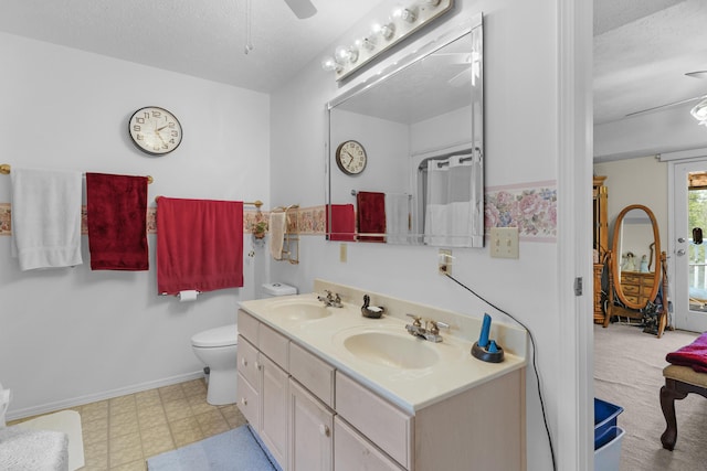 bathroom featuring toilet, a textured ceiling, ceiling fan, and a sink